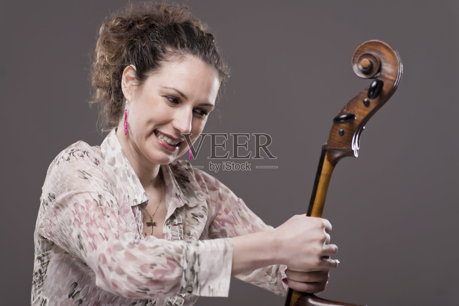 年轻的女大提琴手对她的大提琴很生气照片摄影图片