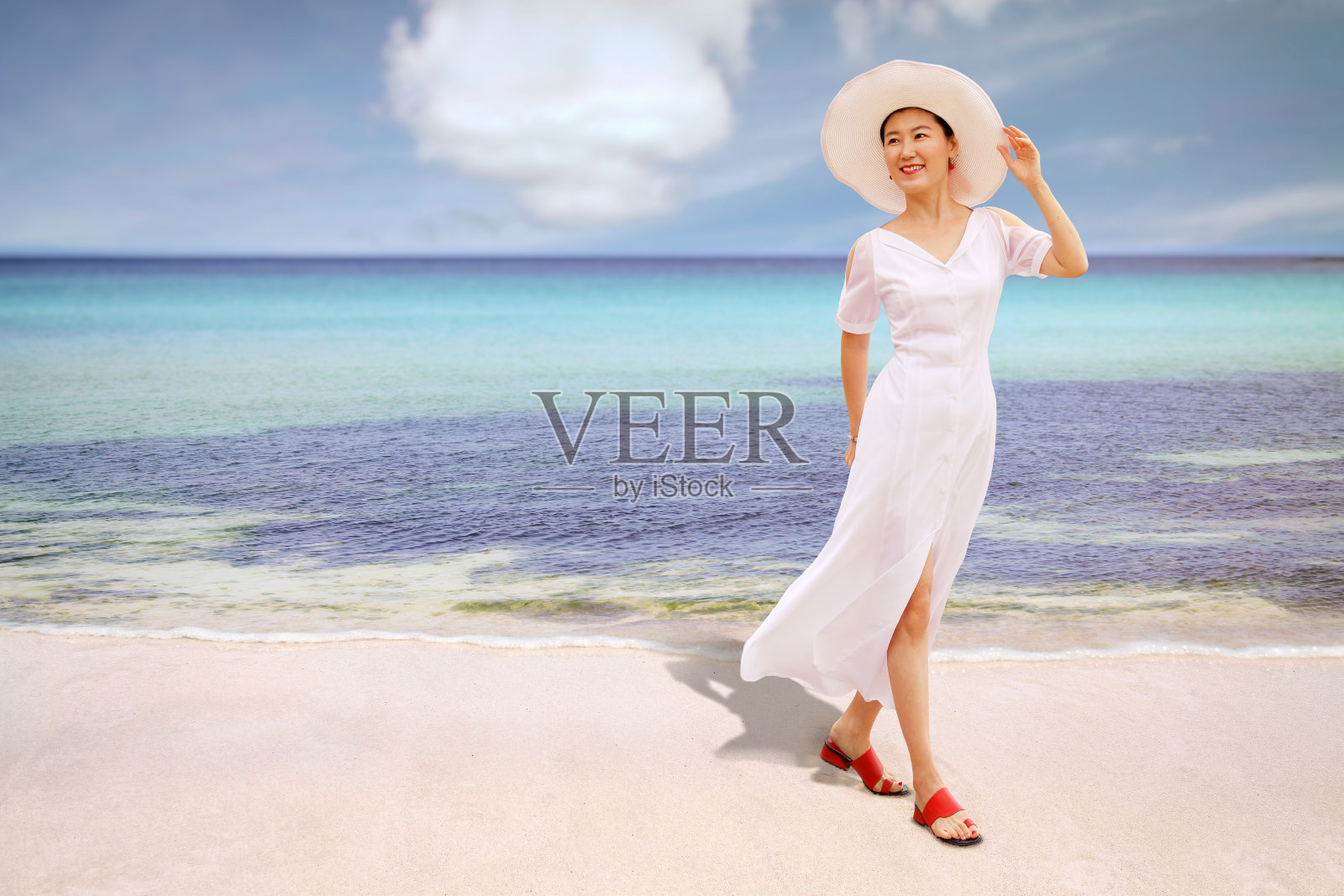 快乐的旅行者女人在白色连衣裙和帽子享受她的热带海滩度假。照片摄影图片