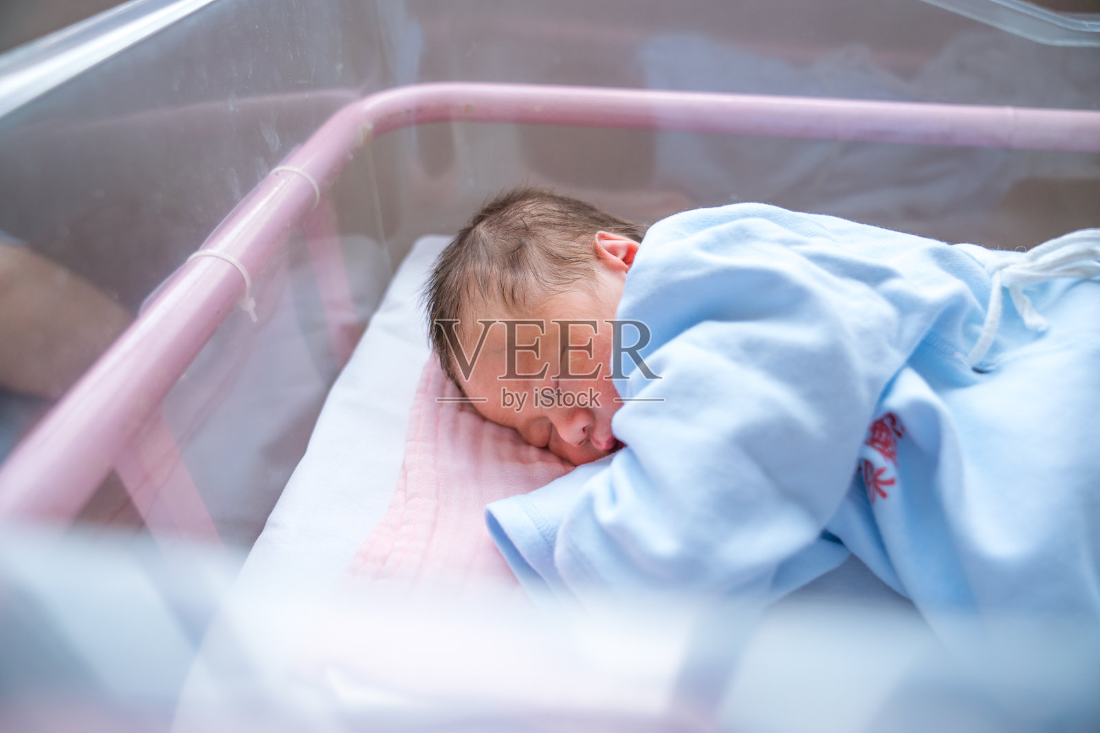 刚出生的婴儿睡在医院的摇篮里照片摄影图片
