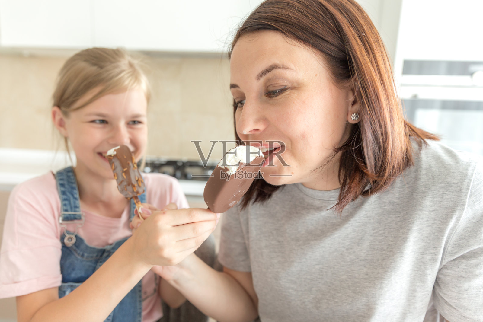 母亲和女儿在厨房吃冰淇淋。良好的亲子关系。幸福的家庭的概念照片摄影图片