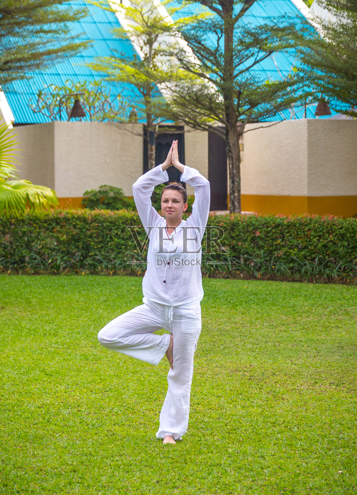 白人妇女穿着白色衣服在绿色草坪上练习瑜伽照片摄影图片