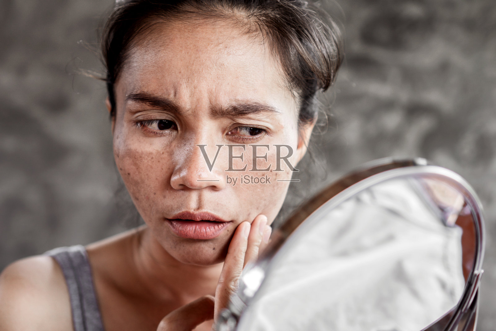 有皮肤问题的亚洲妇女检查她的脸与黑斑，雀斑从紫外线照片摄影图片