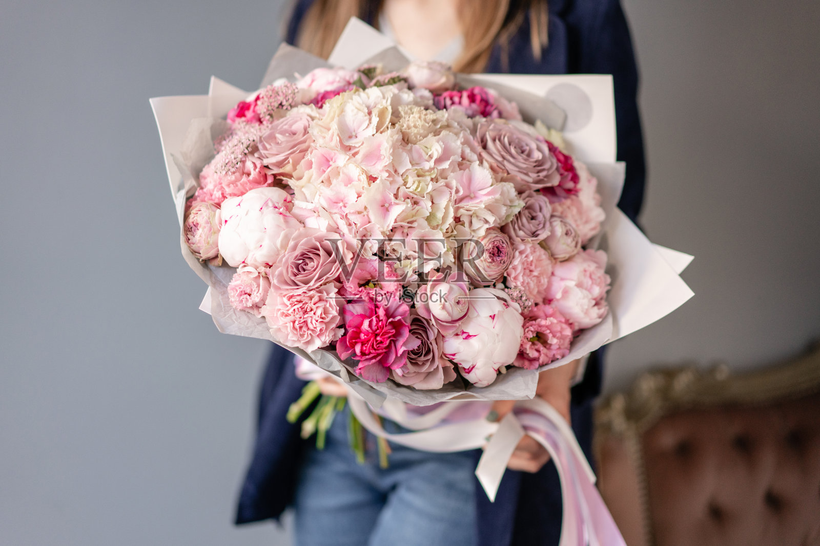 粉色的牡丹和绣球花。女人手里拿着一束美丽的混合鲜花。花店概念。英俊的新鲜的花束。花交付。红色和粉红色。照片摄影图片