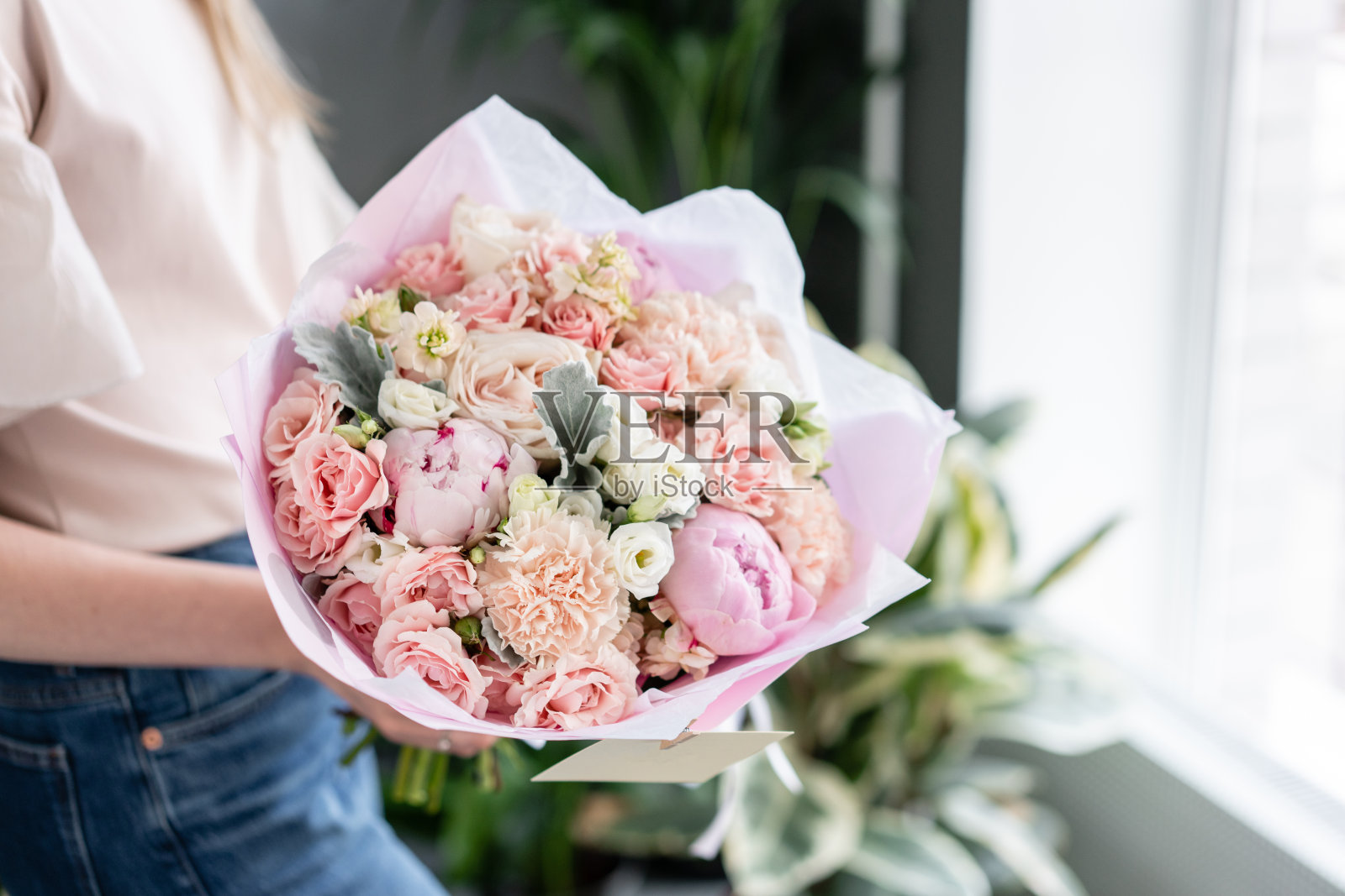 粉色的牡丹。女人手里拿着一束美丽的混合鲜花。花店概念。英俊的新鲜的花束。花交付。红色和粉红色。照片摄影图片