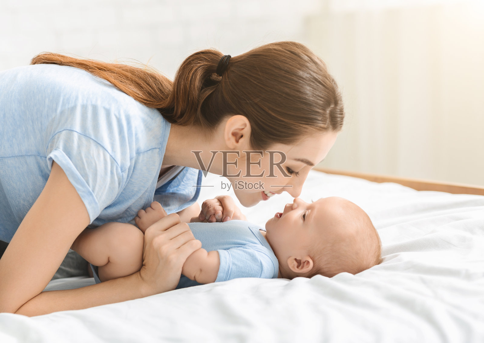 年轻美丽的母亲抚摸着她可爱的新生儿子的鼻子照片摄影图片