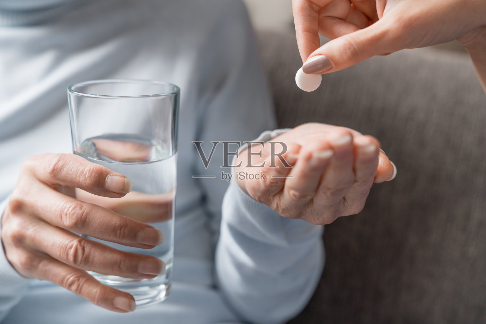 护理护士拿着一杯水给老年妇女吃药照片摄影图片