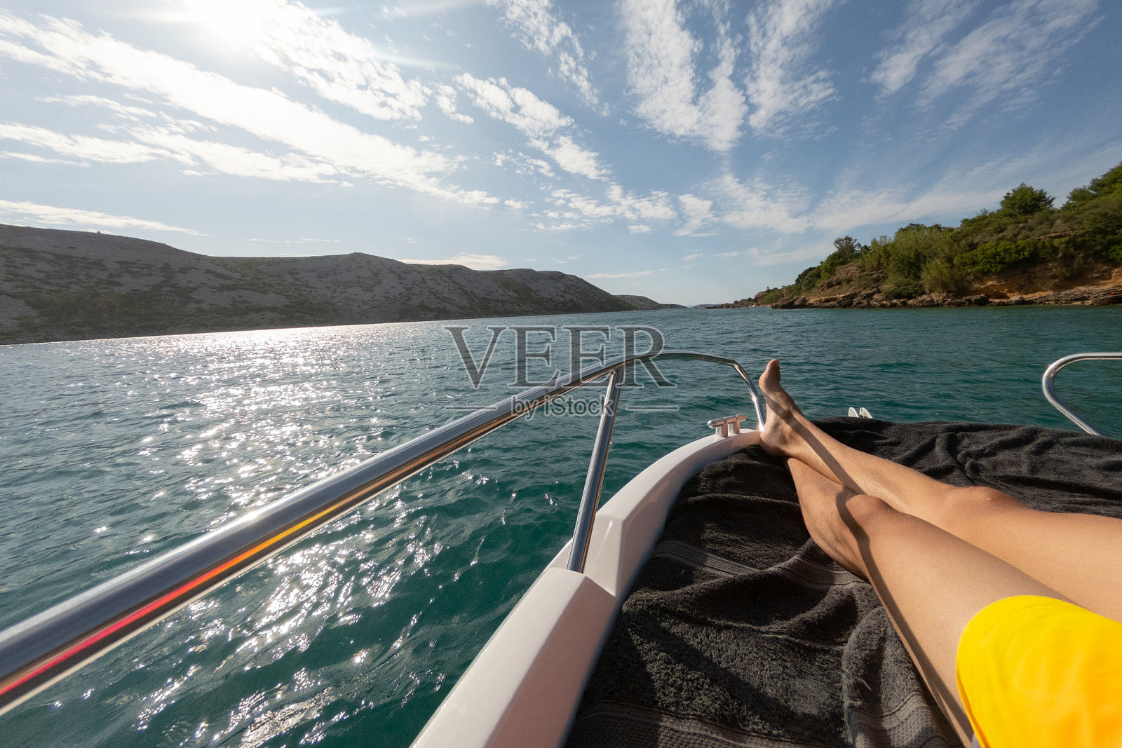 男人和女人的腿躺在游艇上与tiquoise蓝色的大海和海滩与绿色的棕榈树的背景。奢华的夏日度假概念。照片摄影图片