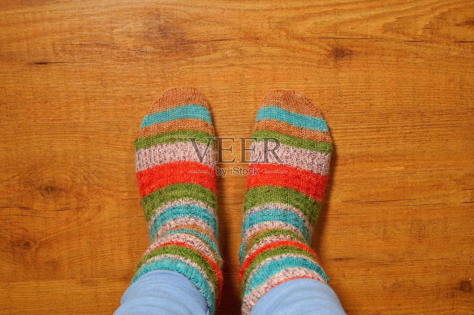 羊毛袜放在木地板上，腿上用针织袜作为乡村生活的象征，冬天的温馨景象照片摄影图片