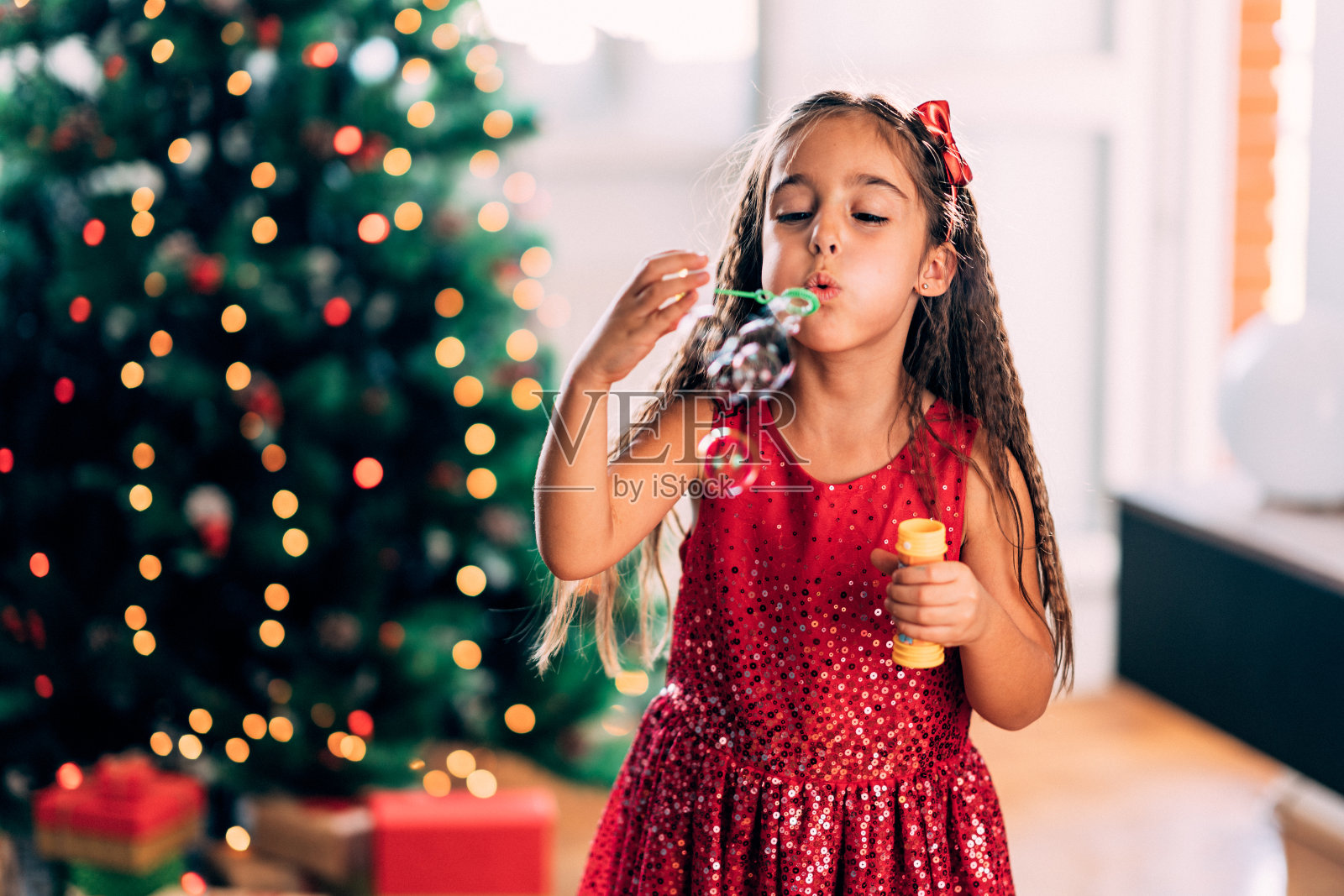 小女孩在圣诞树旁吹泡泡照片摄影图片