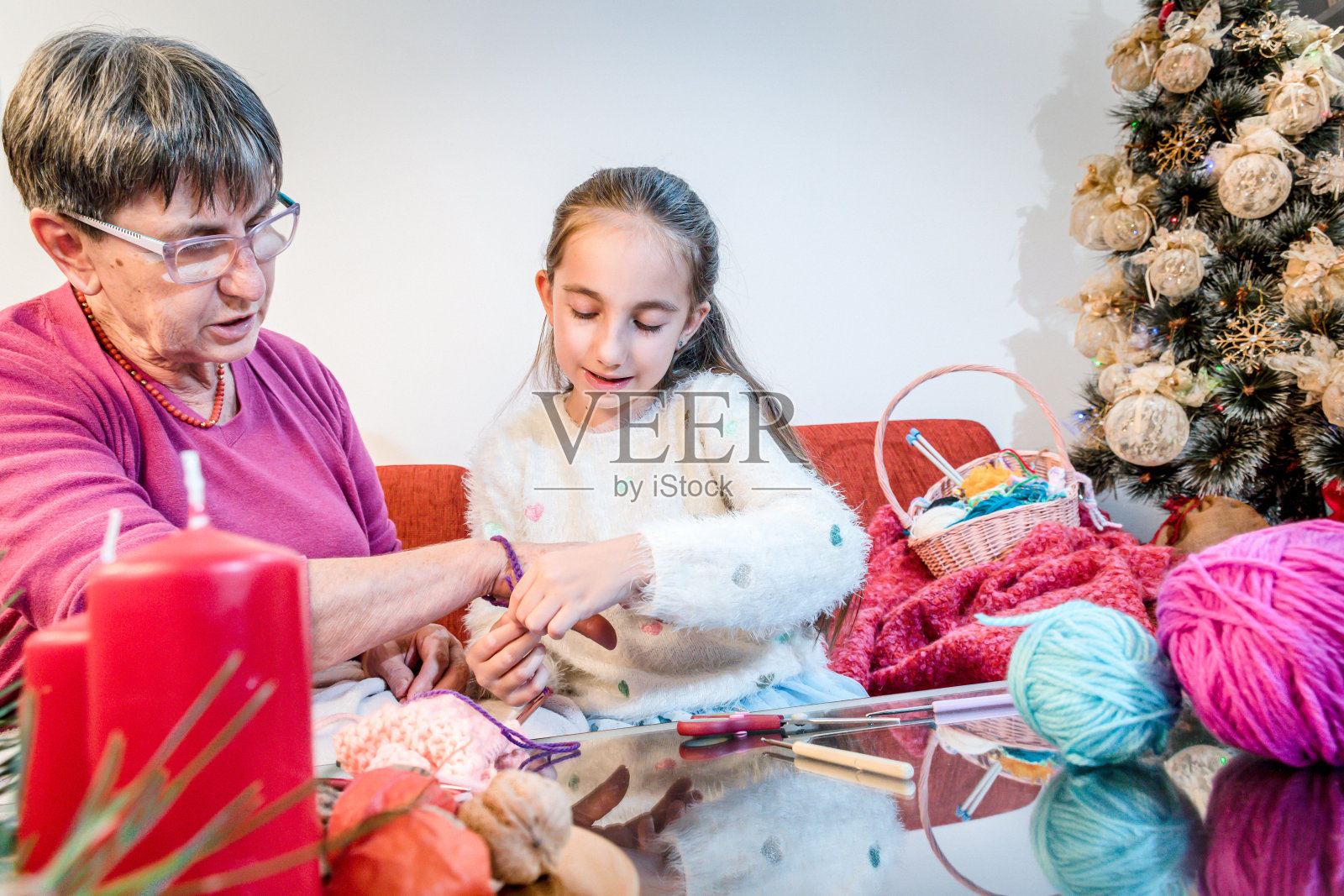 微笑的女孩编织手镯给奶奶在圣诞节时间照片摄影图片