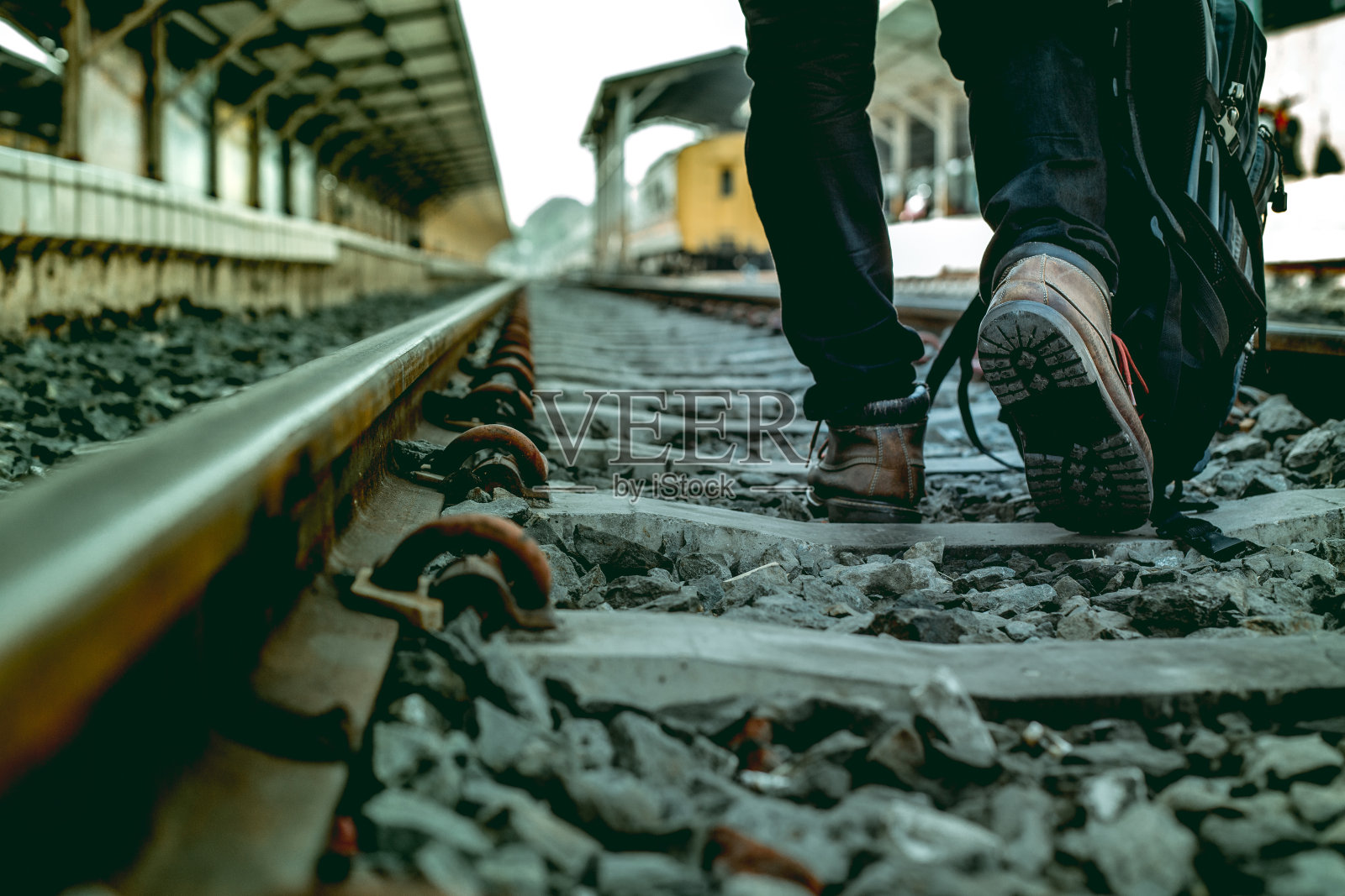 提包的单身青年独自走在铁路上。照片摄影图片