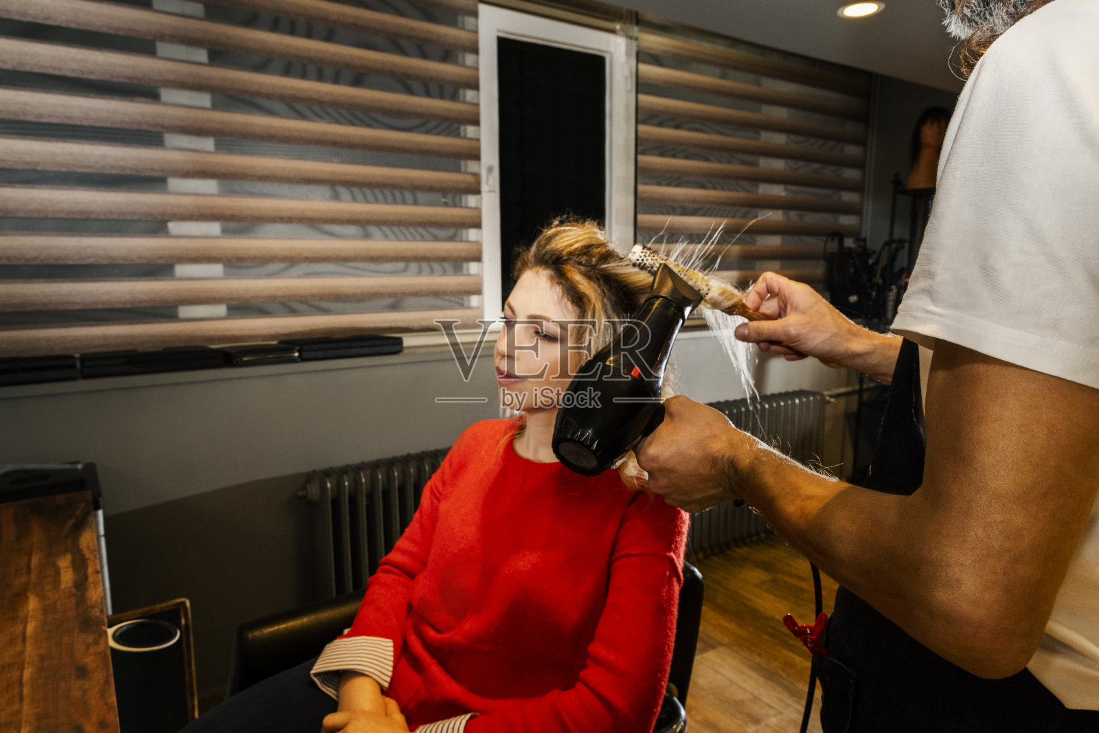 美发师给年轻女子吹干头发照片摄影图片
