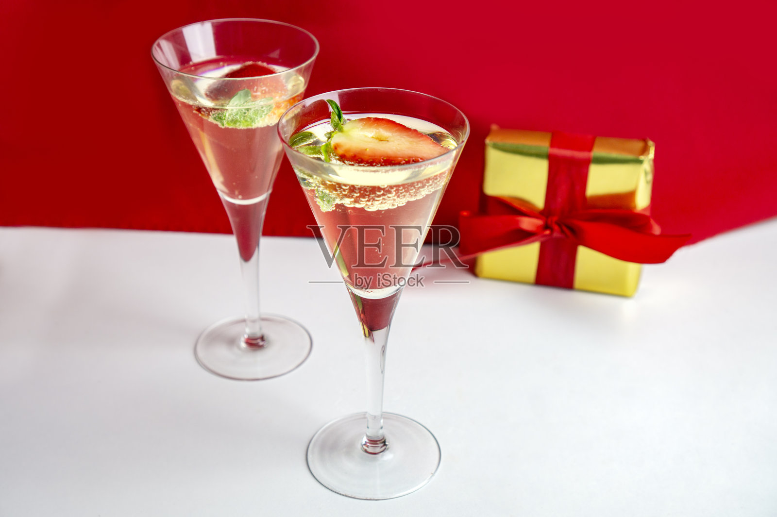 两个香槟杯和草莓和一个礼物的背景情人节的概念照片摄影图片