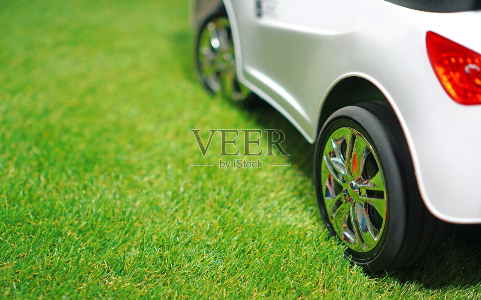 儿童电动汽车在绿色的人造草地上。副本的空间。照片摄影图片