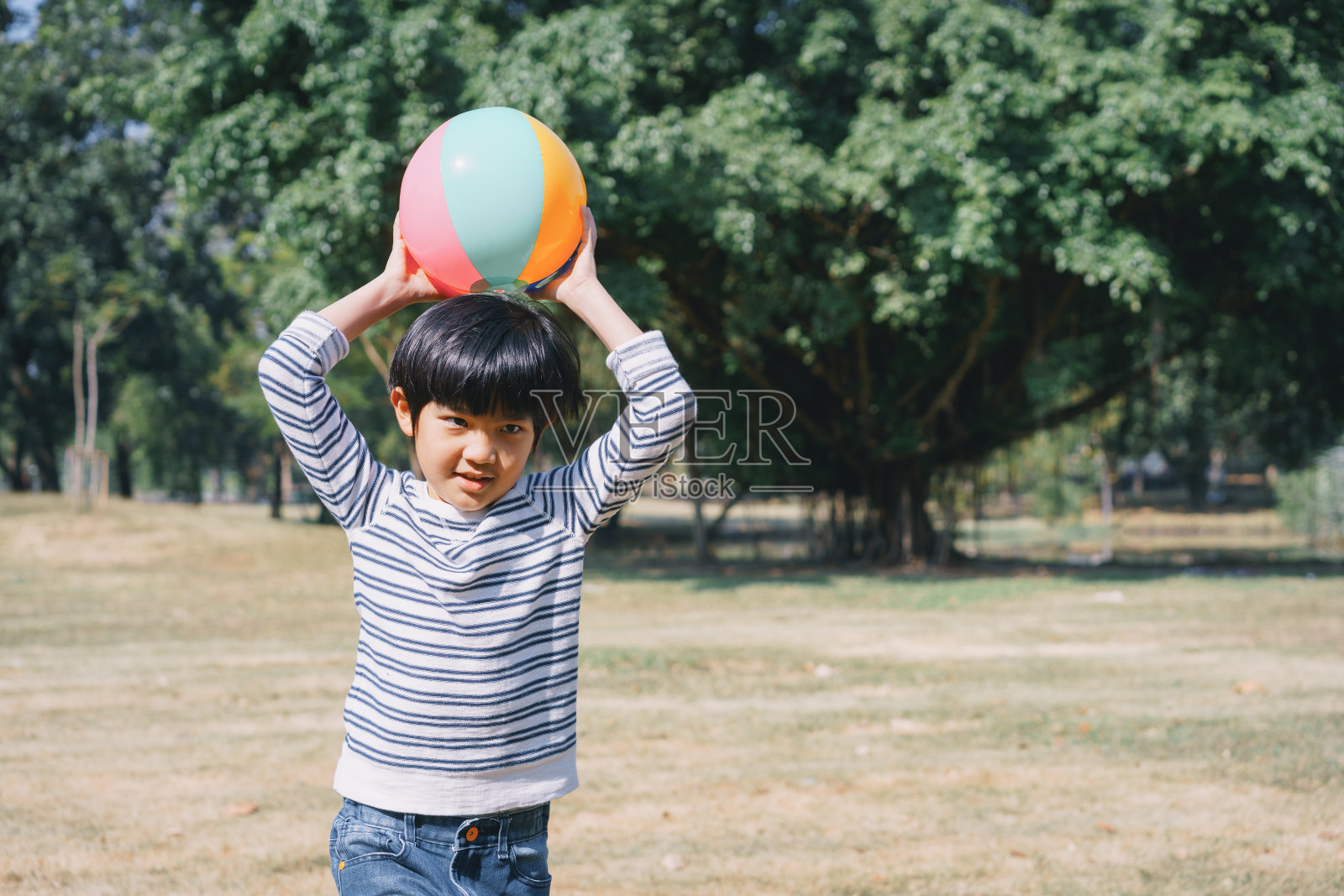 一个亚洲小男孩在公园的草坪上玩球照片摄影图片