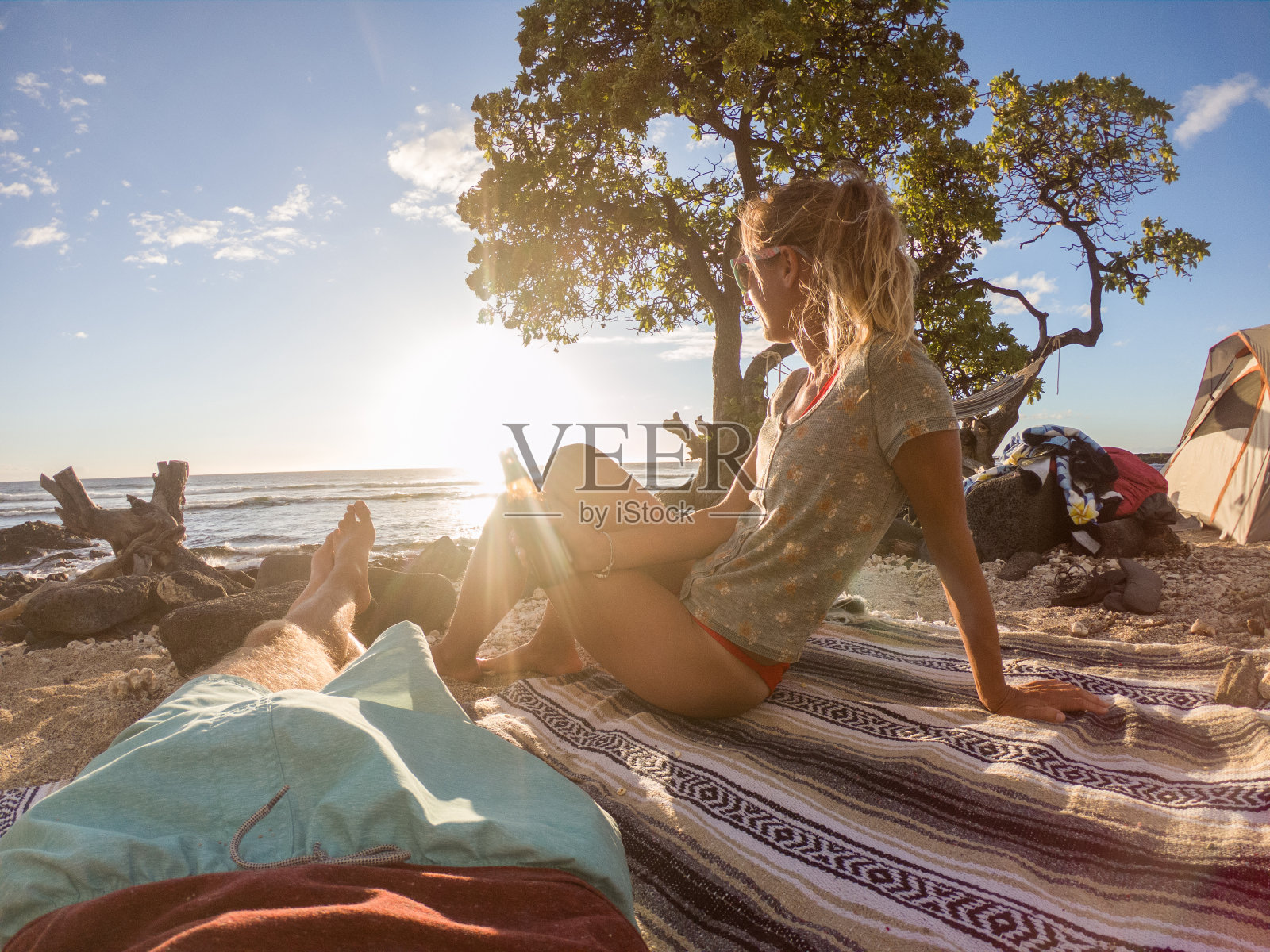 日落时分，一对年轻夫妇在海滩上喝着酒欢呼照片摄影图片