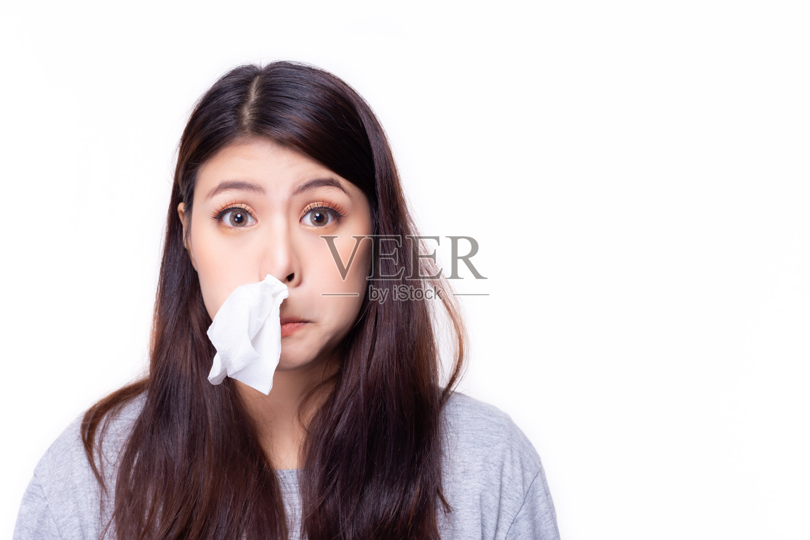 一个亚洲女人把纸巾塞到鼻子里。她鼻塞或流鼻涕。漂亮女孩感冒了或者对天气过敏。现在是冬天或雨季，花粉热正在流行。本空间照片摄影图片