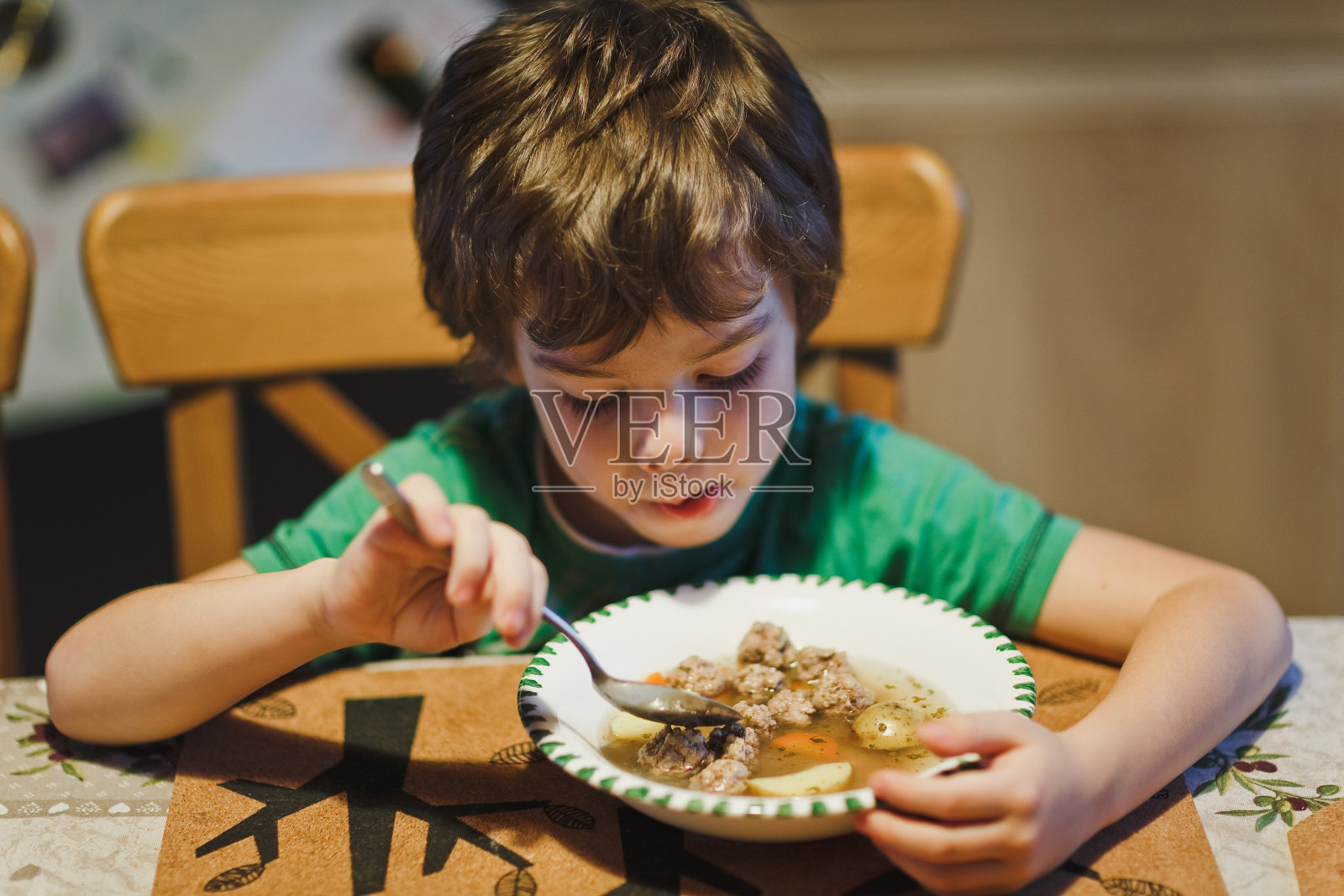 一个小男孩正在吃晚饭。照片摄影图片