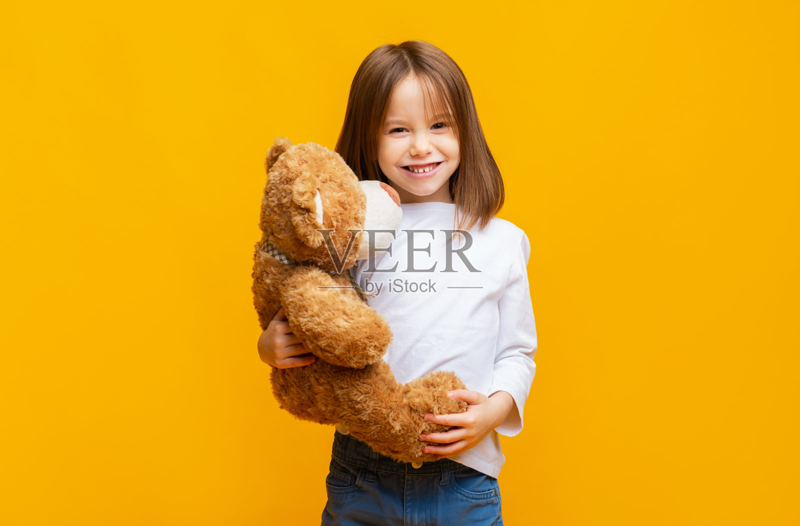 微笑美丽的女孩拥抱大玩具泰迪熊照片摄影图片