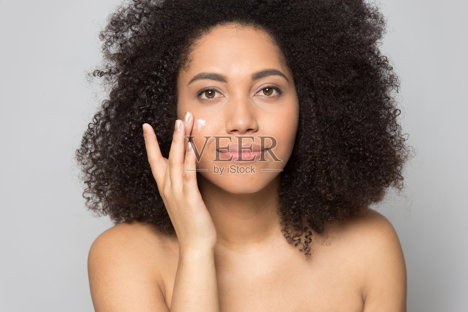 非洲裔美国年轻女士，在皮肤上涂抹保湿霜。照片摄影图片