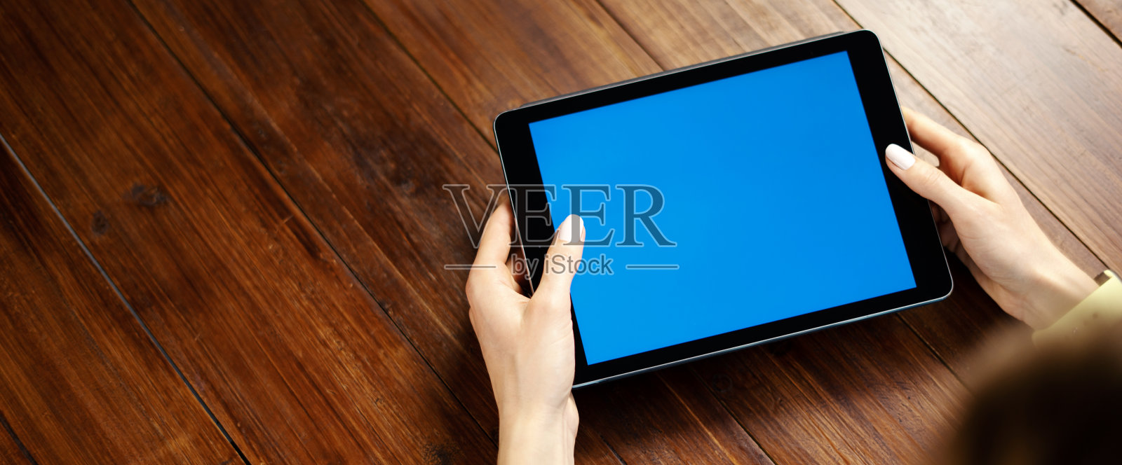 一个女人在木桌上使用空白屏幕的数字平板电脑的模型图像。近距离照片的女性手持有装置水平照片摄影图片