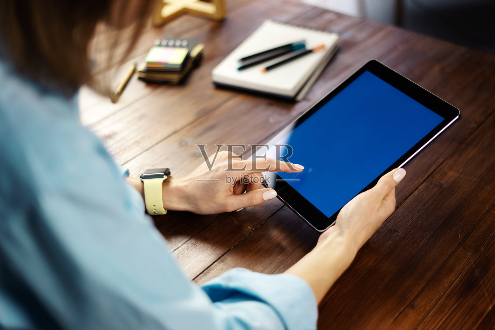 一个女人在木桌上使用空白屏幕的数字平板电脑的模型图像。近距离拍摄的女性手握装置垂直照片摄影图片