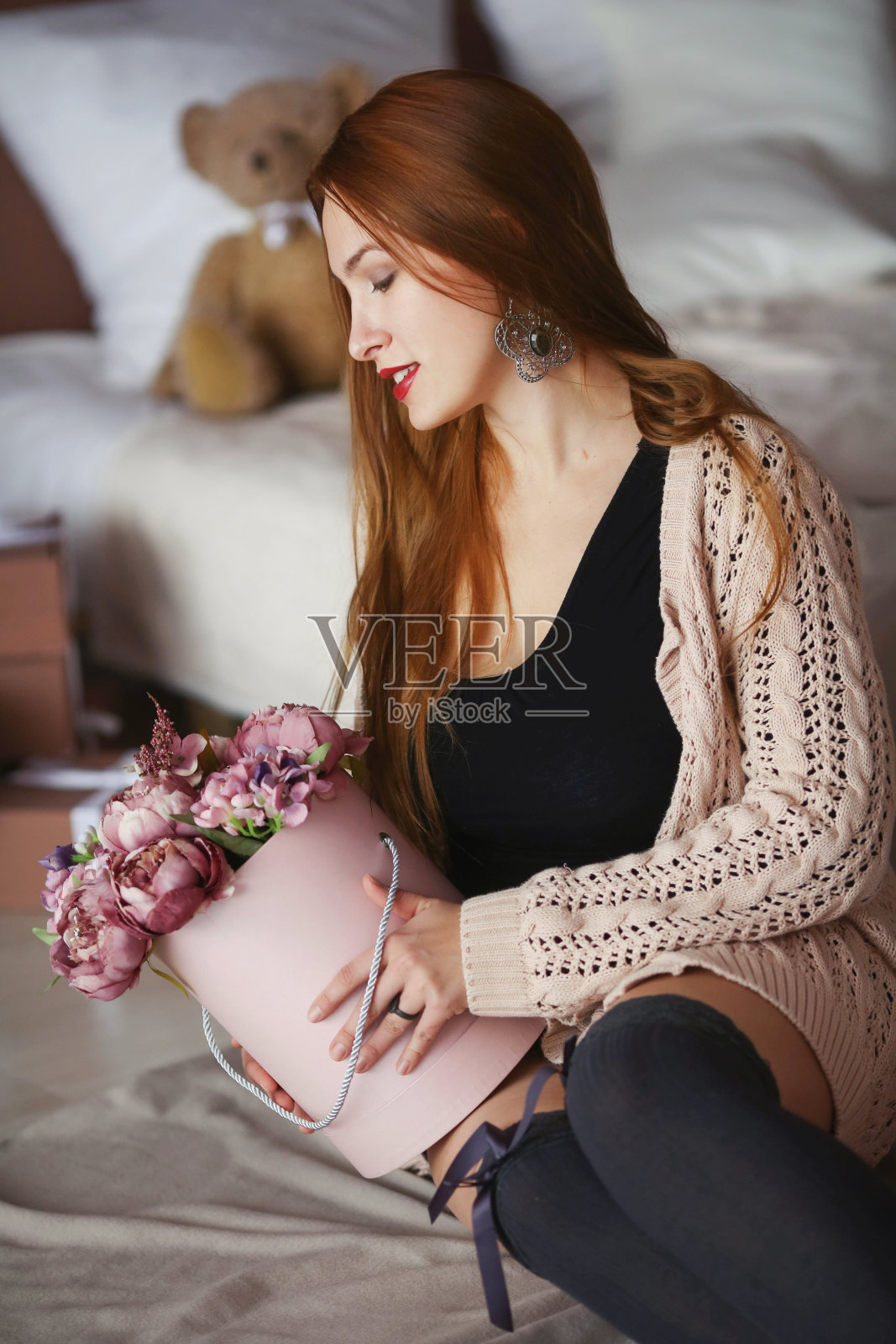 一个漂亮的女人，一头红长发，穿着一件暖暖的粉红色毛衣，手里拿着一个花篮照片摄影图片