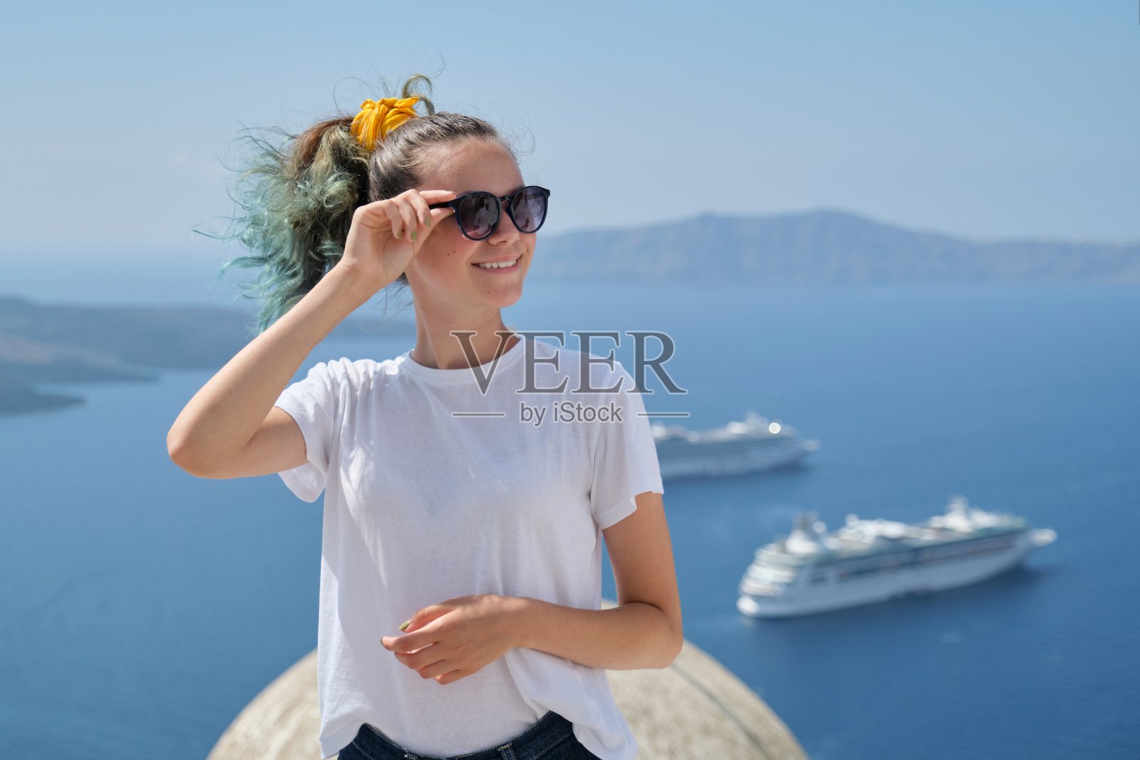 年轻的女游客面带微笑，背景风景如画的海景与邮轮照片摄影图片