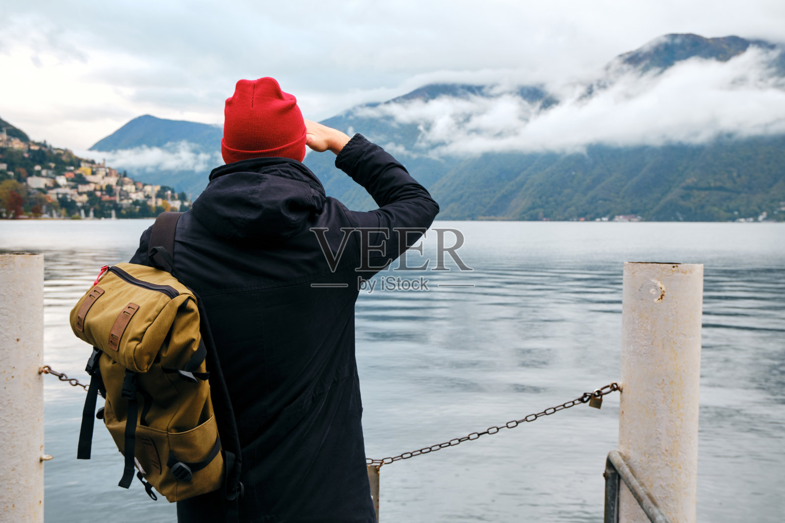 背包男子在卢加诺码头欣赏全景。人在旅行。卢加诺湖，阿尔卑斯山南坡。在瑞士的风景。令人惊叹的户外风景。广州提契诺。冒险的生活方式照片摄影图片