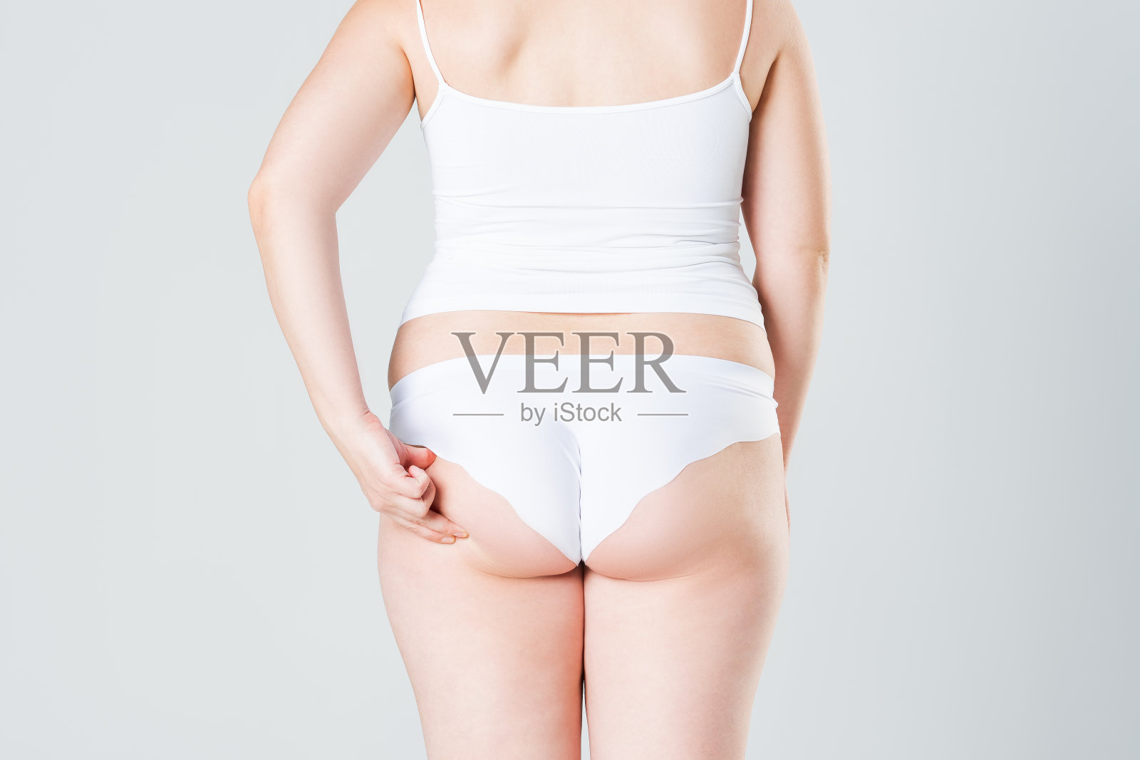 超重女性与肥胖的腿和臀部，肥胖女性的身体在灰色的背景照片摄影图片