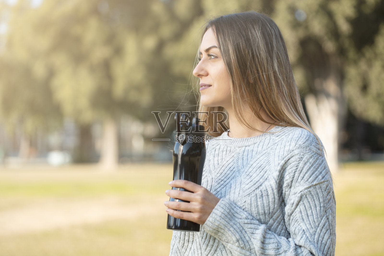 年轻漂亮的女人用烧瓶喝水，健康的生活方式照片摄影图片