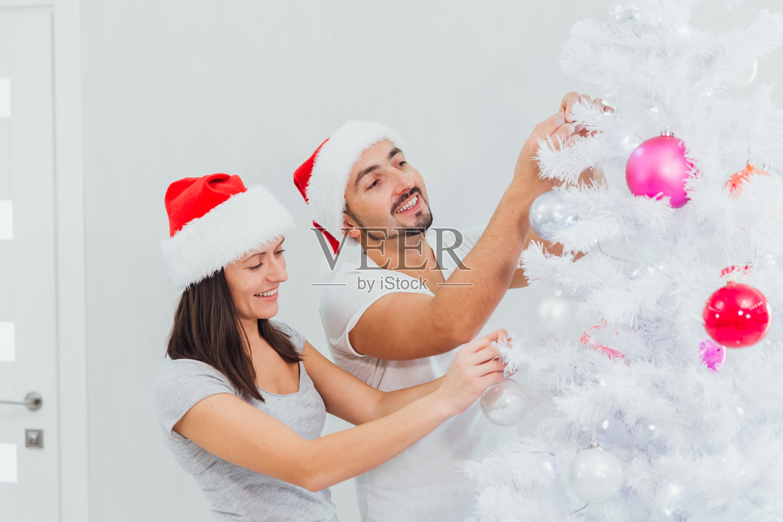 可爱的年轻夫妇装饰圣诞树照片摄影图片