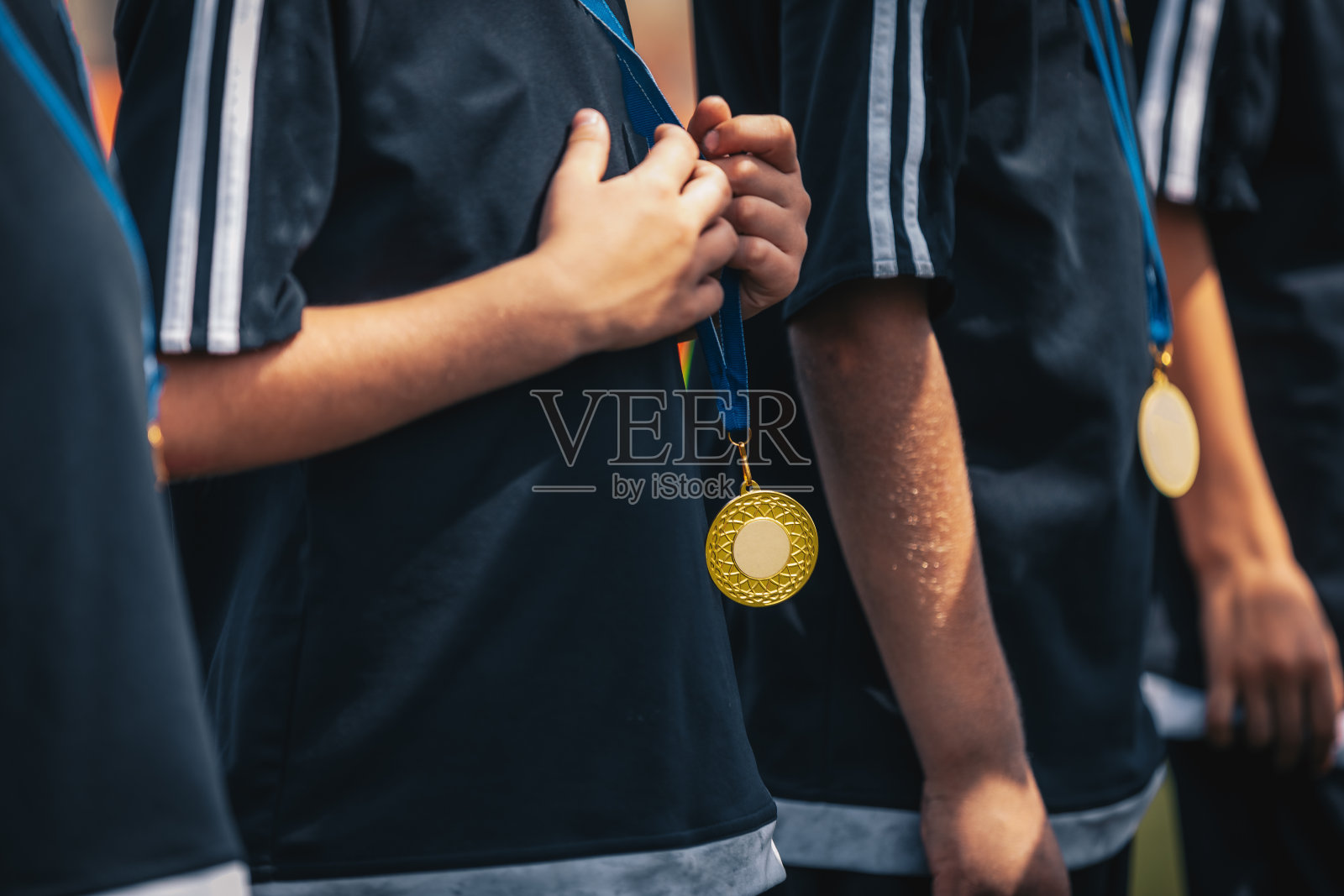 在庆祝活动中，运动员们拿着金牌站成一排。奖牌挂在年轻运动员的脖子上照片摄影图片