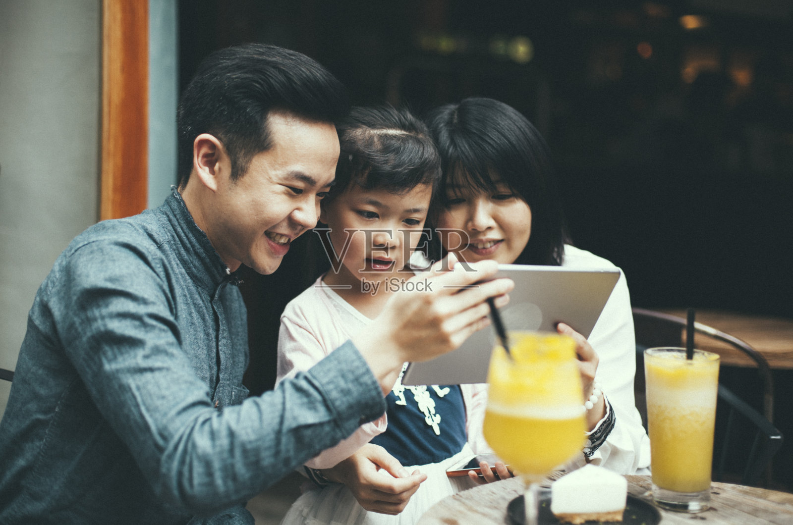 亚洲家庭在café与数字平板电脑的乐趣照片摄影图片