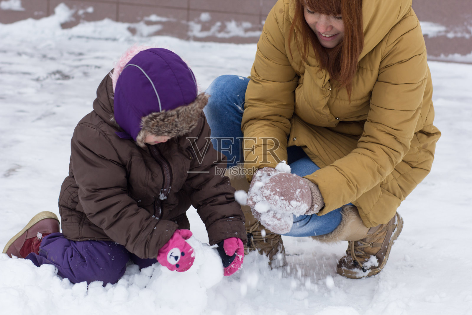 妈妈和孩子在冬天的公园里玩雪球照片摄影图片