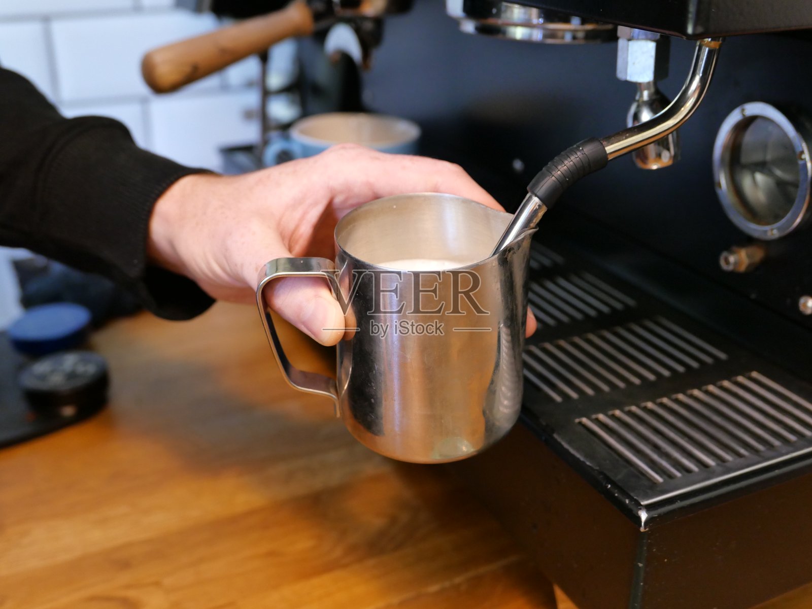 咖啡师用蒸汽喷嘴加热一小壶牛奶照片摄影图片