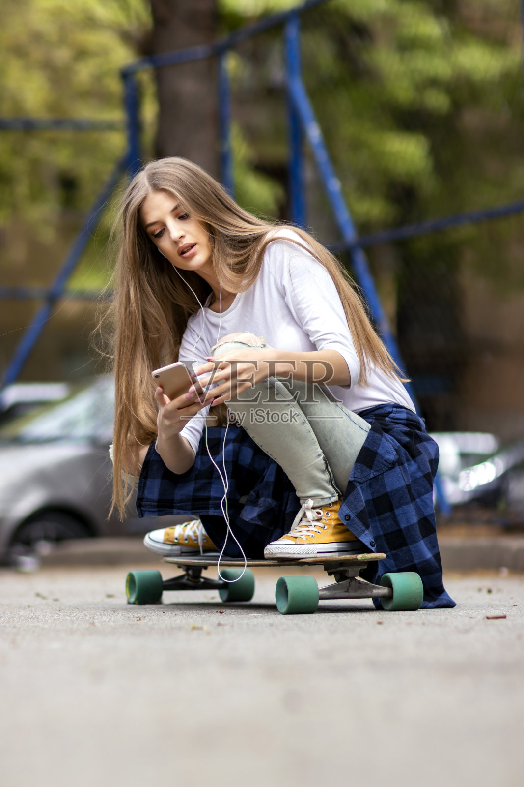 的乐趣。女滑板手正在街上用手机照片摄影图片