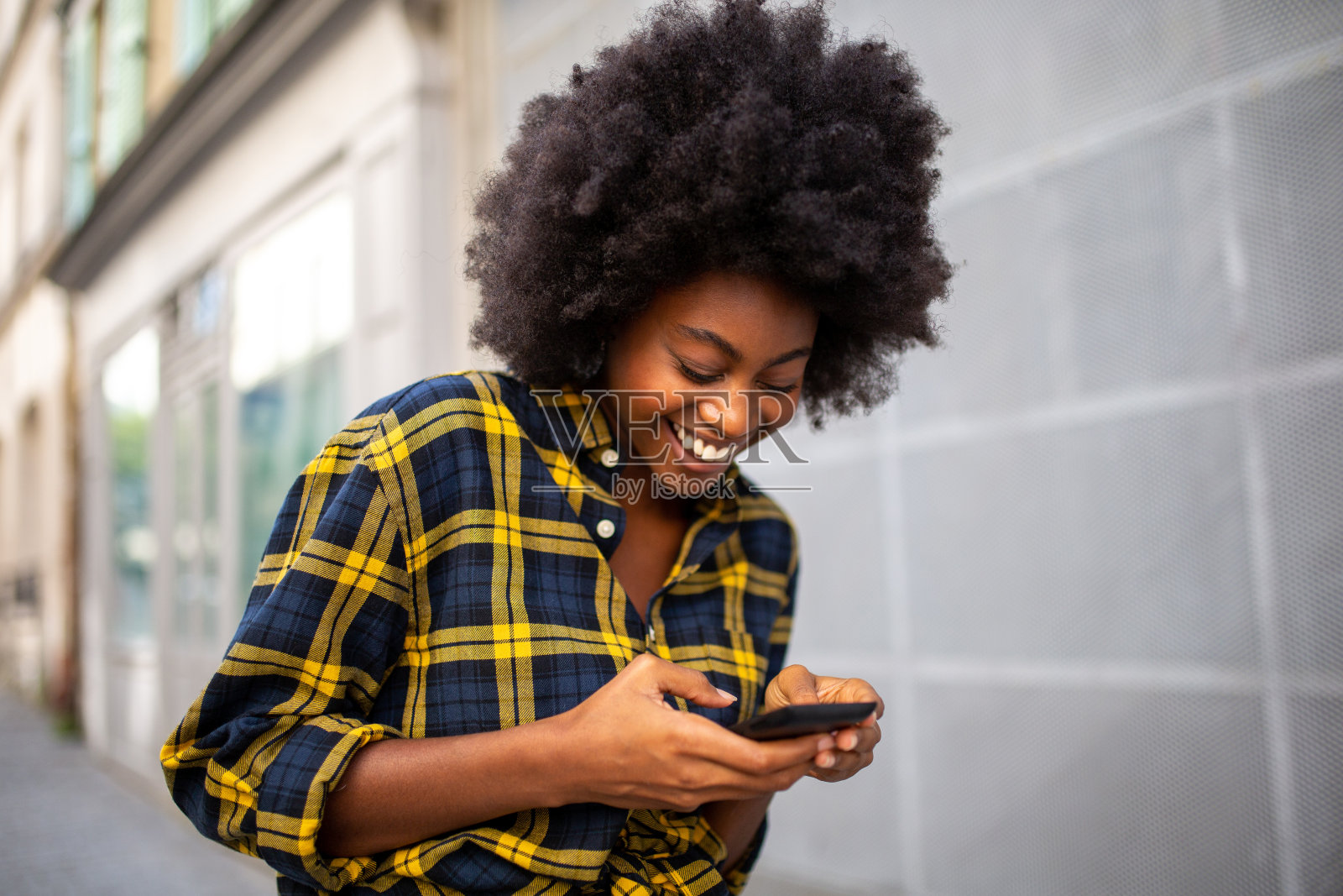 一个年轻的黑人女人走在街上看手机照片摄影图片