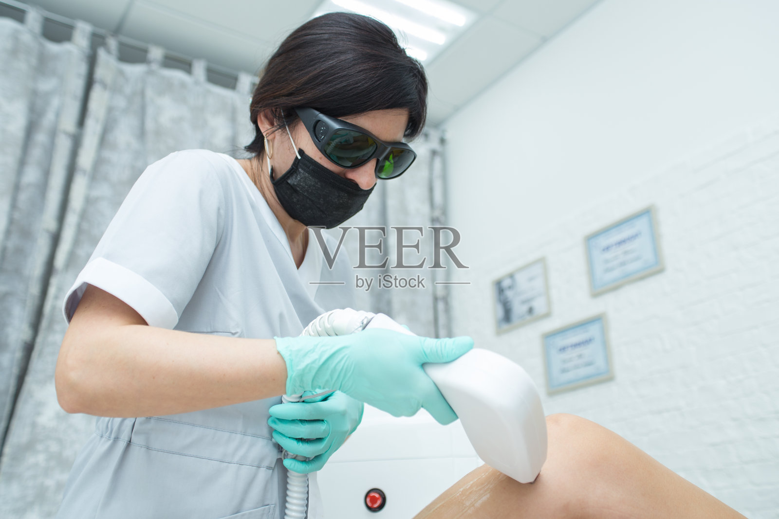 美容师用医用激光去除女性腿部的毛发。照片摄影图片