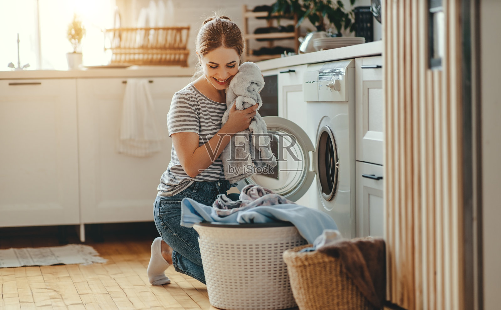 快乐的家庭主妇在洗衣房和洗衣机照片摄影图片