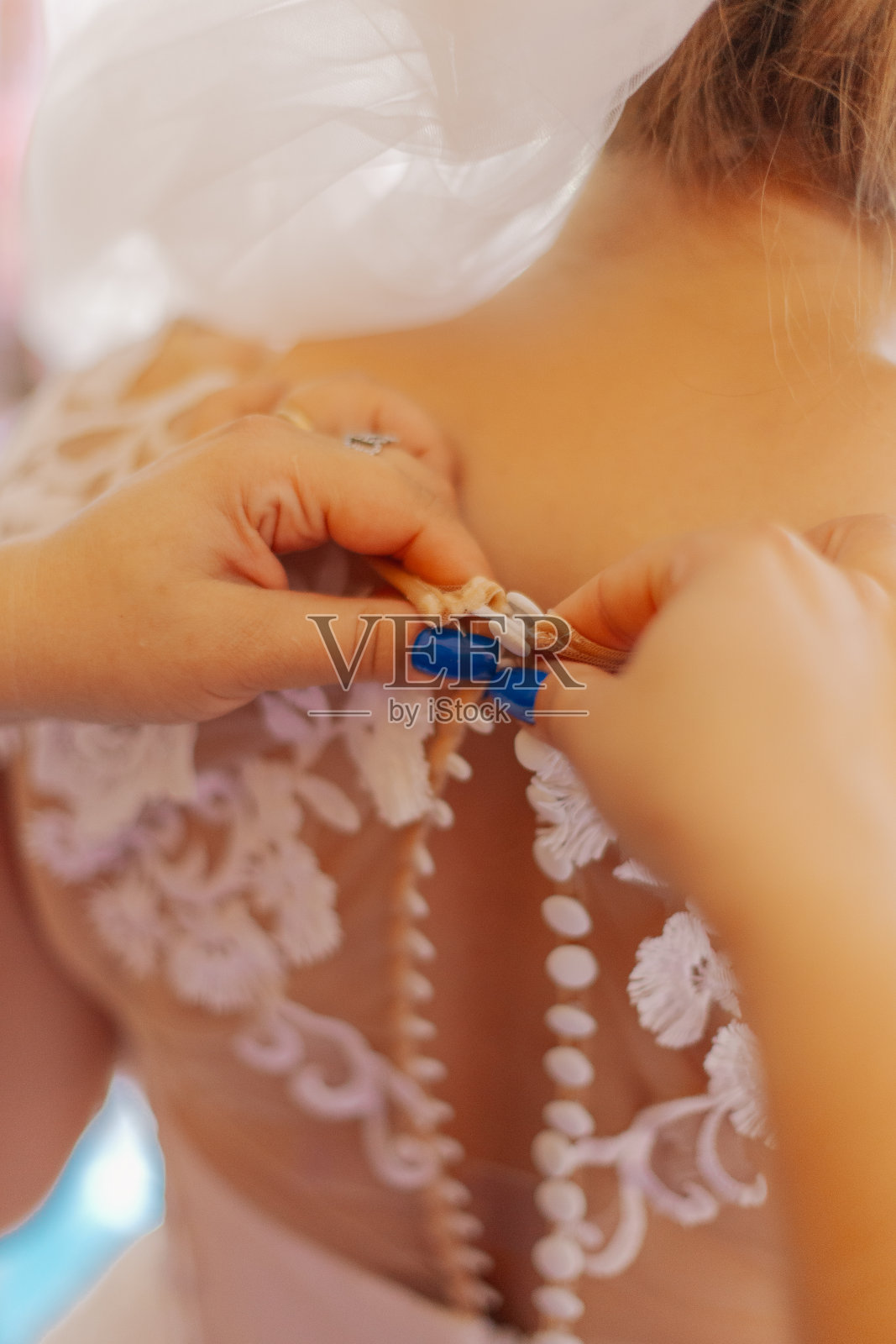 一个年轻的新娘扣着结婚礼服。快乐的婚礼照片摄影图片