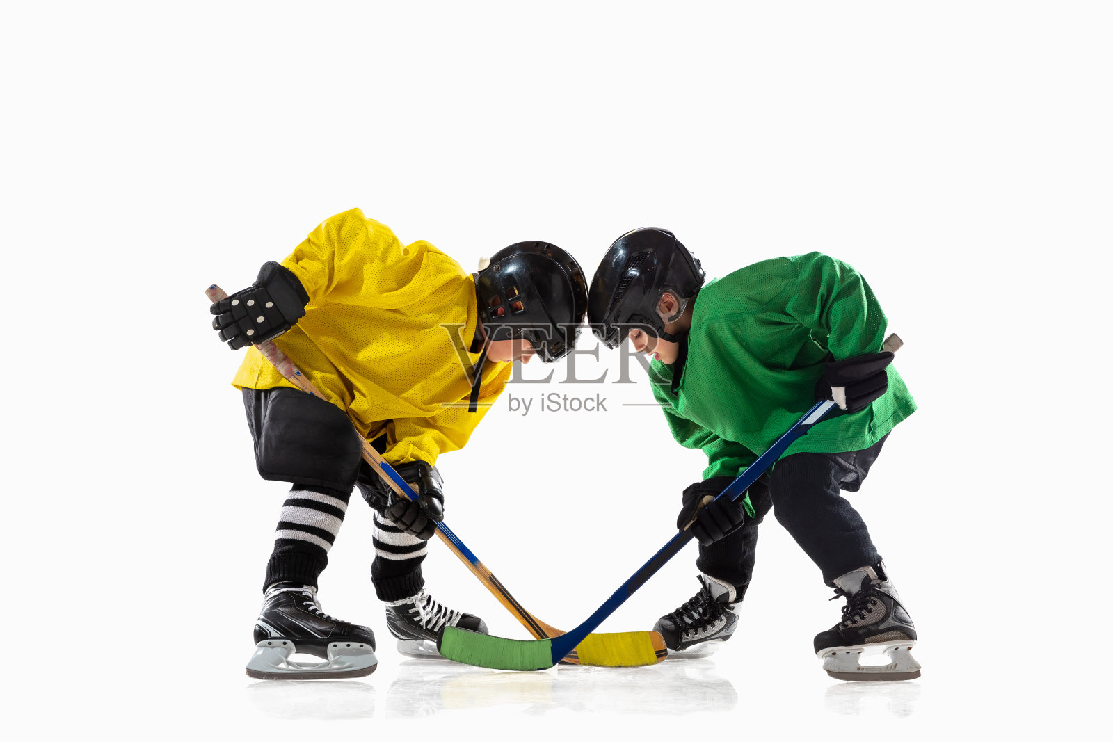 冰球小球员与棒子在冰上球场和白色的工作室背景照片摄影图片