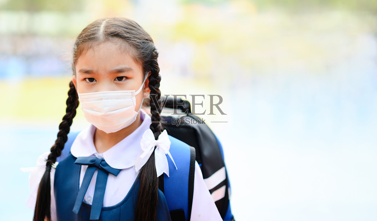 在泰国曼谷，一名女学生戴着口罩对抗空气烟雾污染照片摄影图片
