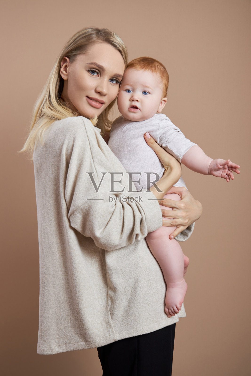 那位妇女怀里抱着一个婴儿。一个年轻母亲在生完孩子后的肖像。年轻的家庭照片摄影图片