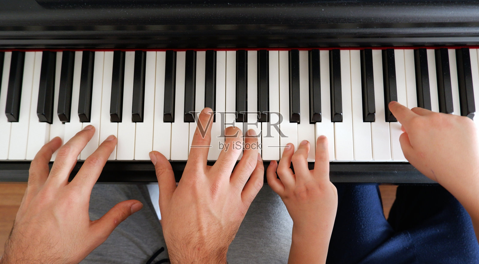 一个小男孩和他的弟弟正在弹钢琴。照片摄影图片