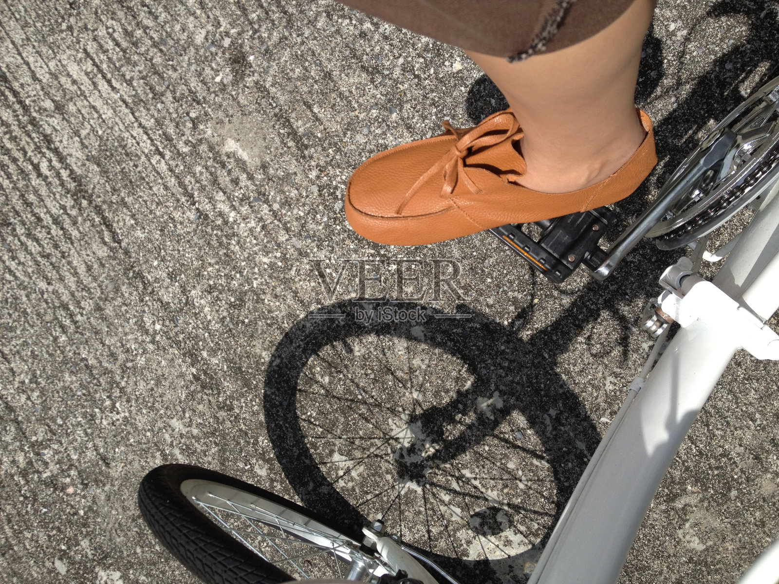 俯视图拍摄的男人穿着棕色的裤子和皮鞋是骑白色的自行车照片摄影图片