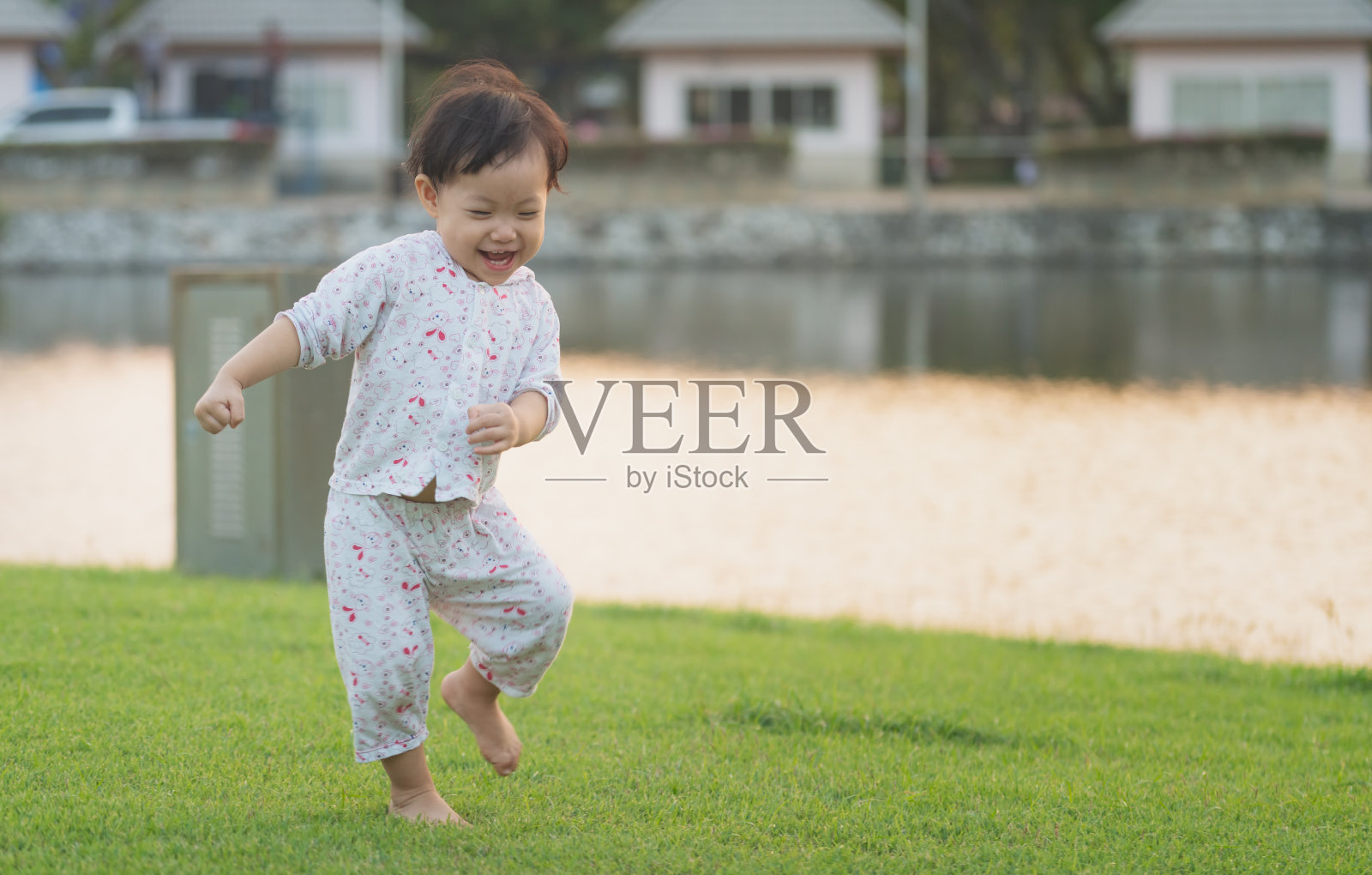 亚洲小女孩在草坪上玩得很开心，晚上在公园里享受。幸福的家庭的概念照片摄影图片