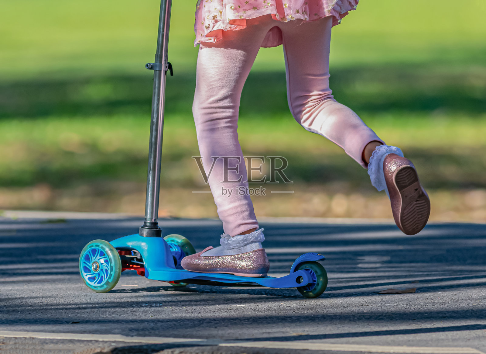 一个穿着粉红色裙子的女孩在玩滑板照片摄影图片