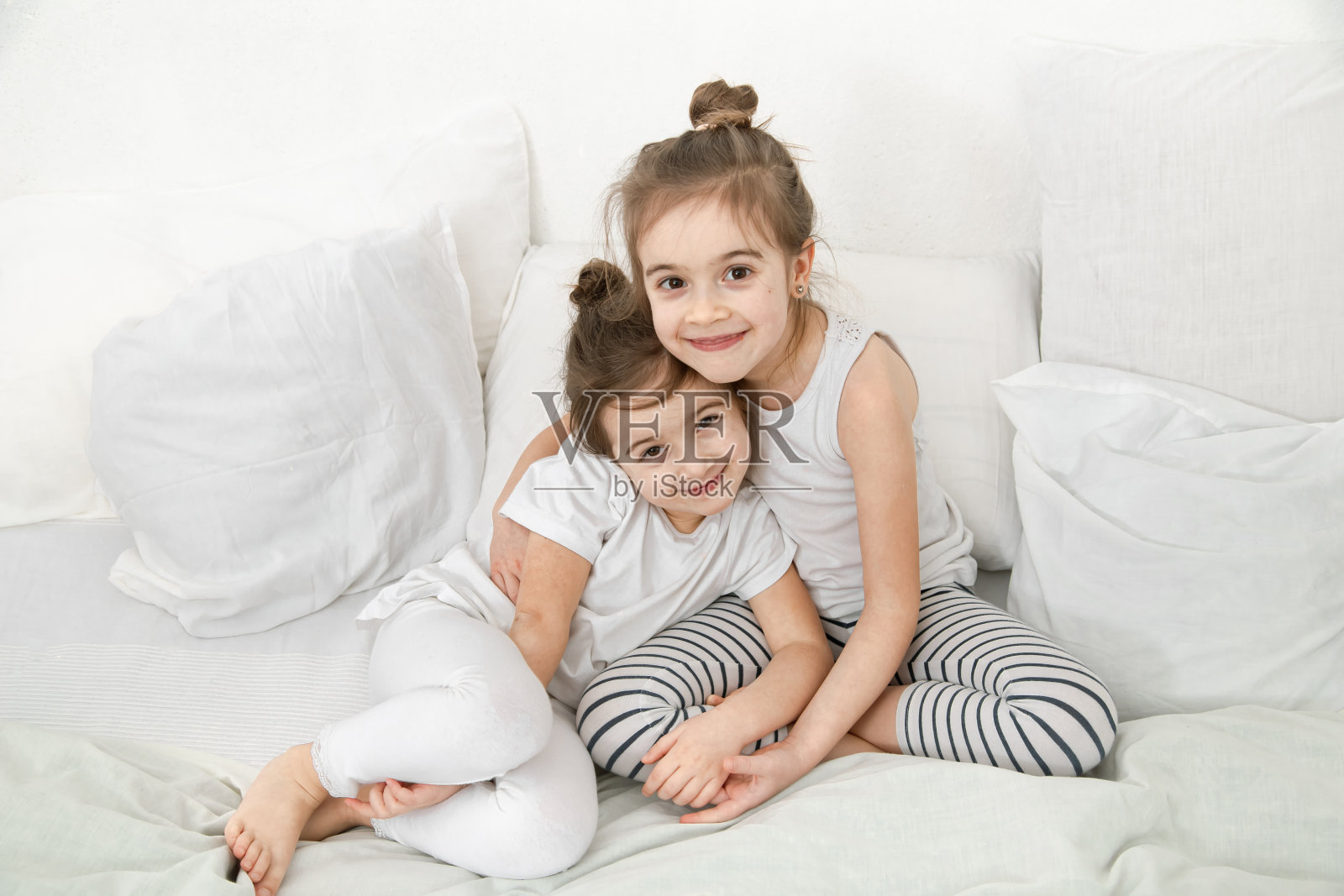 两个可爱的小妹妹依偎在卧室的床上。照片摄影图片