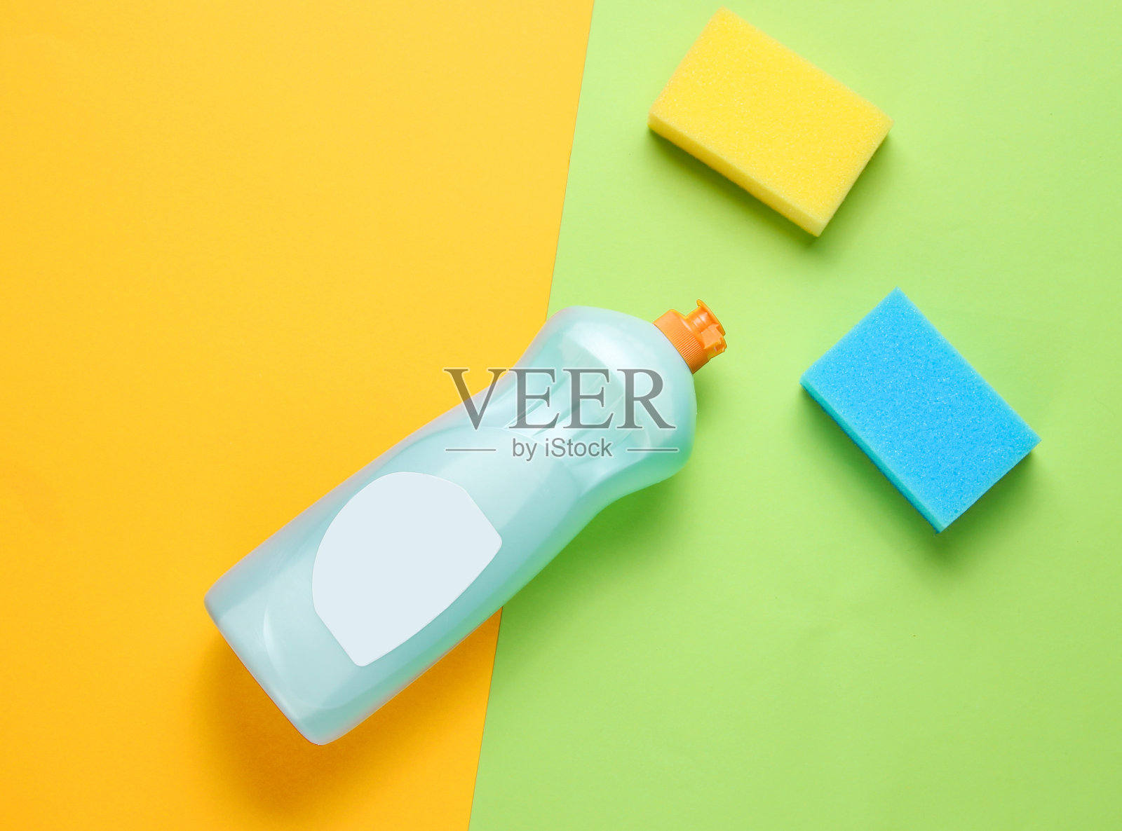 一瓶洗碗用的洗涤剂，海绵在彩色纸上做背景。俯视图照片摄影图片